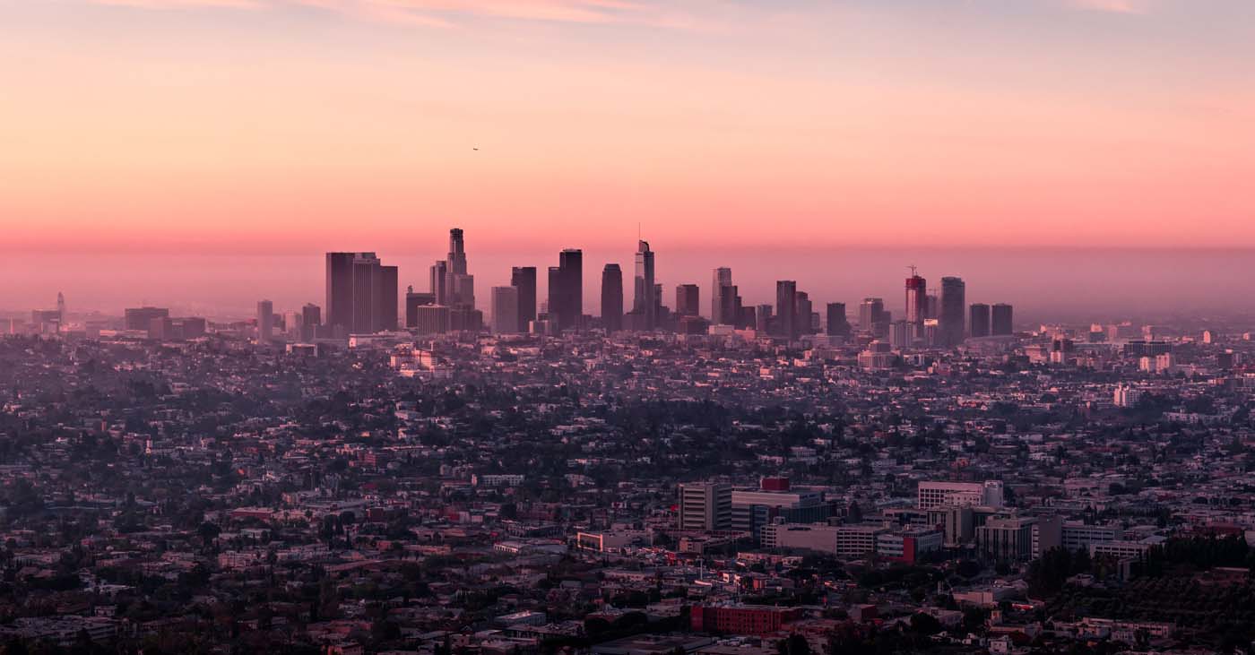 Los Angeles at sunrise. The city's office buildings create a striking backdrop against the pink-tinged low-level clouds