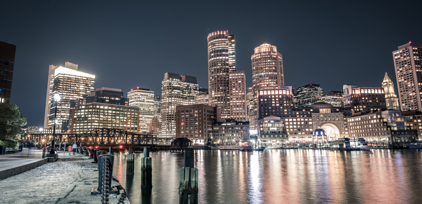 nighttime view across the boston inner harbor water at commercial real estate massachusetts downtown boston skyscrapers with their office lights on