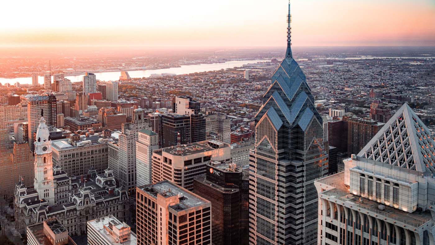 daybreak aerial view across downtown philadelphia pa commercial real estate office towers with the delaware river shimmering and winding through the background