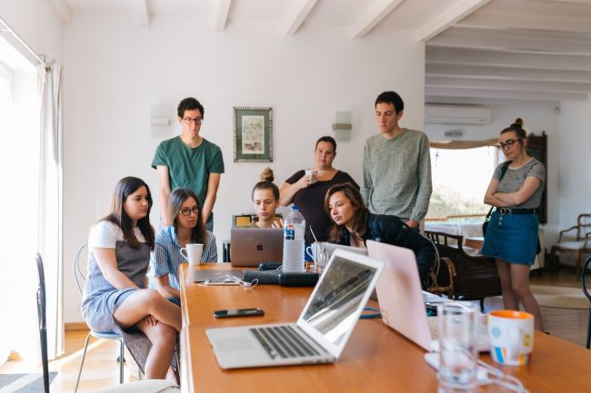 colleagues gather around laptop at offices.net