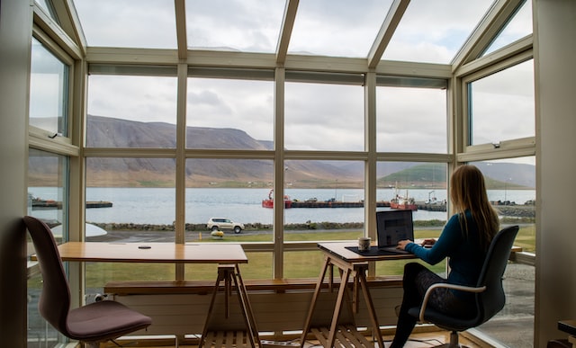 woman working remotely with view of lake and mountains since decentralization of cities changed the u.s. office space market image at offices.net