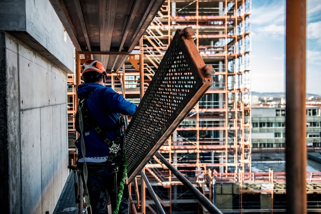 man working on scaffolding around building being constructed in houston image at offices.net