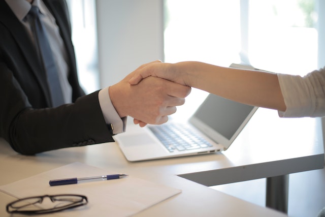 male and female office workers shake hands at desk image at offices.net