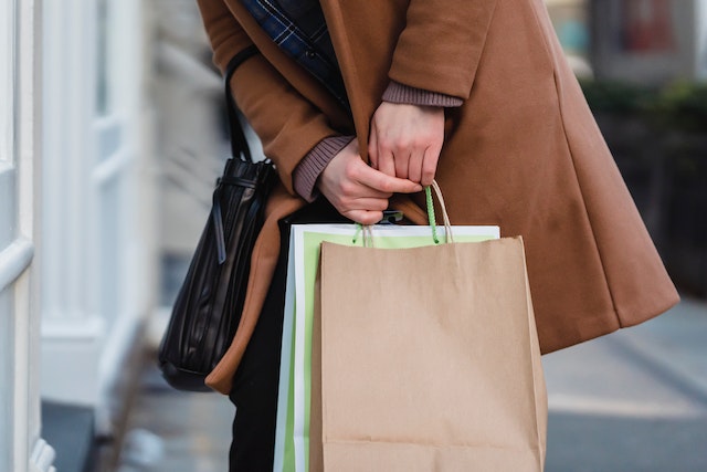 woman wearing brown winter coat holding shopping bags while retrieving keys from pocket image at offices.net