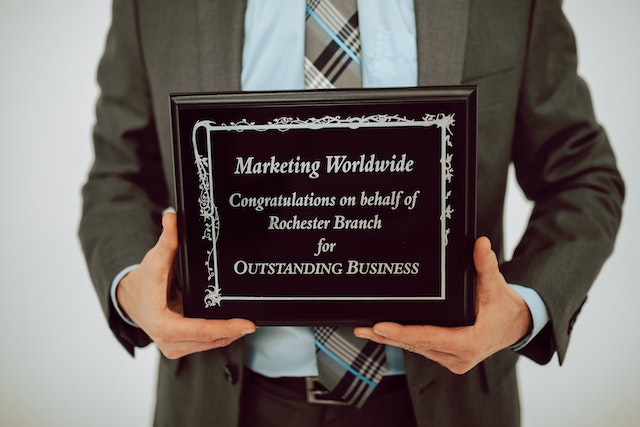 man holding commemorative plaque award for outstanding business image at offices.net