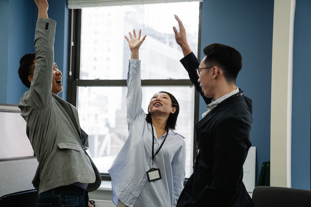 three colleagues in a circle with arms raised celebrating image at offices.net