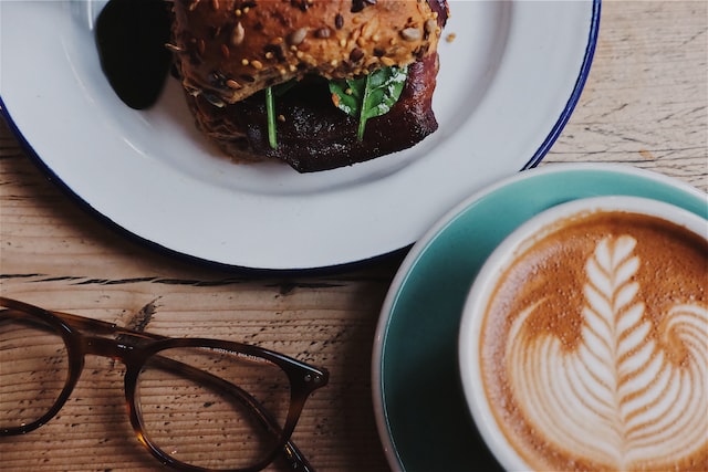 close up of table laden with eyeglasses sandwich and cup of coffee image at offices.net