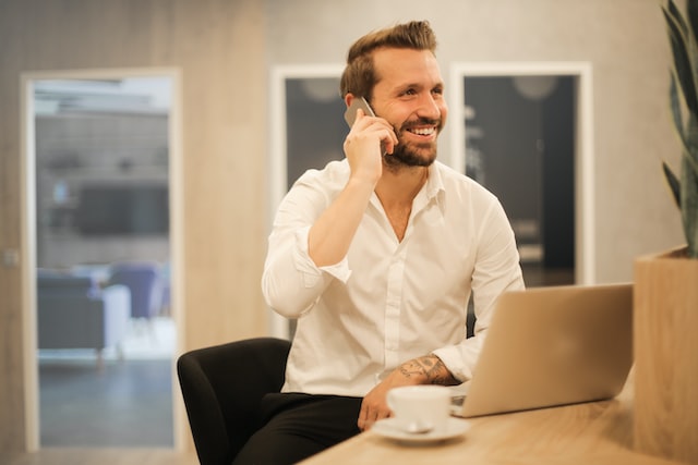 a man sitting on the phone at a desk whilst enjoying a coffee image at offices.net
