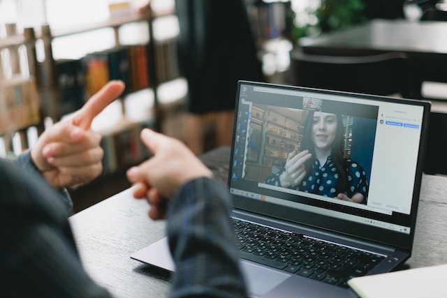 a man performs sign language to a woman he is on a videocall with on his laptop who is also signing image at offices.net