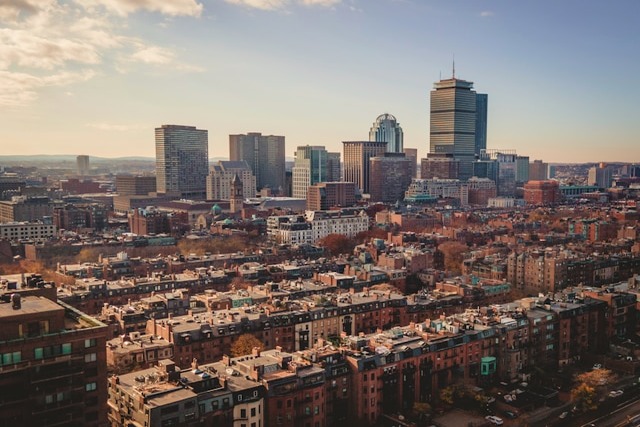A late afternoon view across the red brick-faced buildings of sprawling Back Bay, with Boston’s skyline in the background. Image at Offices.net.