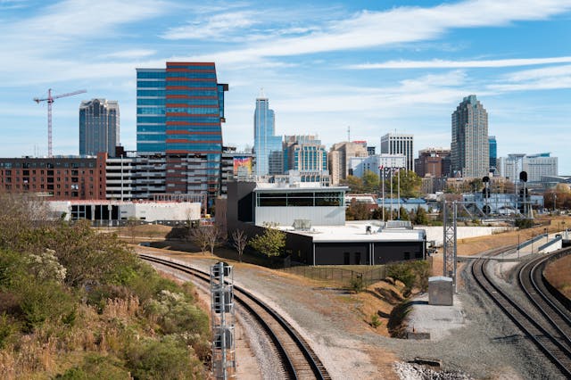 A daytime view towards the city skyline of Raleigh, North Carolina, from above the train tracks just outside the city. Image at Offices.net.